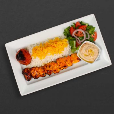 chicken kebab plate with rice, tomato, hummus, and salad.